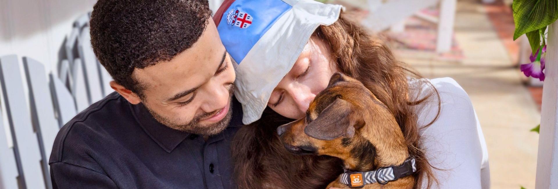Image of man and woman cuddling with a foster dog